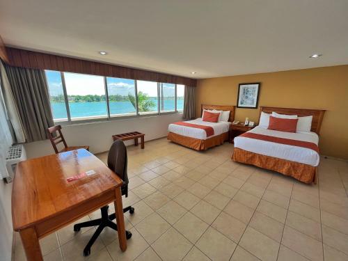 Cette chambre comprend deux lits, un bureau et une table. dans l'établissement Best Western Riviera Tuxpan, à Tuxpan