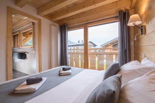 a bedroom with a large bed with a large window at The Alpine Lodge in Les Gets
