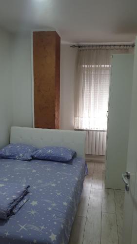 um quarto com uma cama com lençóis azuis e uma janela em Apartmani Borko 1-2 em Loznica