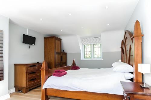 a bedroom with a large bed and a television at Robin Cottage in Chipping Campden