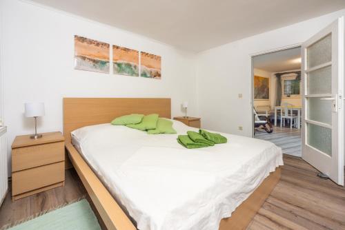 sypialnia z dużym białym łóżkiem z zielonymi poduszkami w obiekcie Greenhouse Adria w mieście Bribir