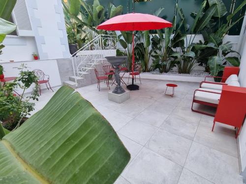 a patio with a red umbrella and chairs and tables at Palms Luxury Suites Sanremo in Sanremo