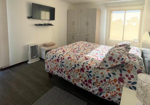 a bedroom with a bed with a colorful comforter and a window at Casa Catrianca, Punta de Lobos in Pichilemu