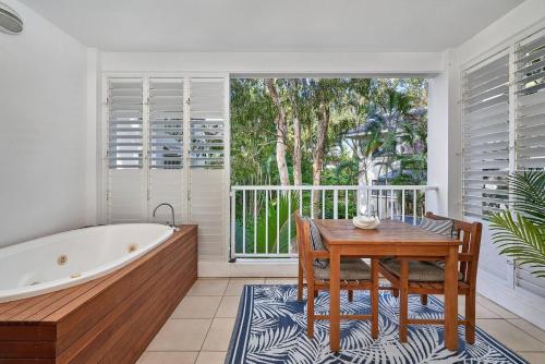 a bathroom with a bath tub and a table and a table and a tablektop at Chic Resort Living at Luxury Beach Club and Spa in Palm Cove