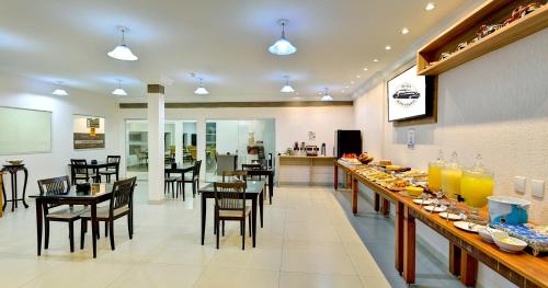 a restaurant with tables and chairs and a bar at Hotel Bons Tempos in Rio Verde