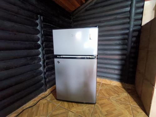 a refrigerator in a room with a black wall at Cabañas San Rafael in Palmares