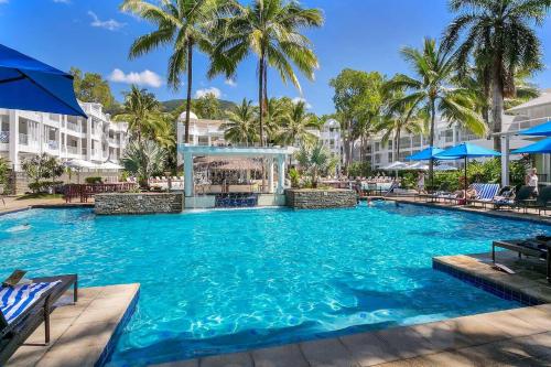 a large pool at a resort with palm trees at Chic Resort Living at Luxury Beach Club and Spa in Palm Cove