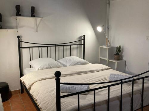 ein Schlafzimmer mit einem schwarzen Bett mit weißer Bettwäsche in der Unterkunft Le Cardinale - Un Voyage en Provence - 2 chambres avec parking in Aix-en-Provence