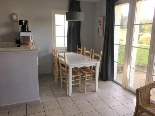 kuchnia z białym stołem i krzesłami oraz oknami w obiekcie Maison Fort-Mahon-Plage, 3 pièces, 4 personnes - FR-1-482-39 w mieście Fort-Mahon-Plage
