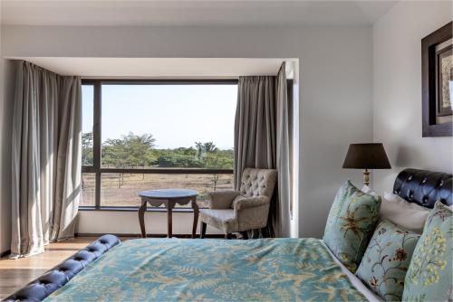 a bedroom with a bed and a chair and a window at Ol Pejeta Mansion in Nanyuki