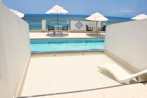 a swimming pool with a table and chairs and an umbrella at La Suite Praia Hotel in Caucaia