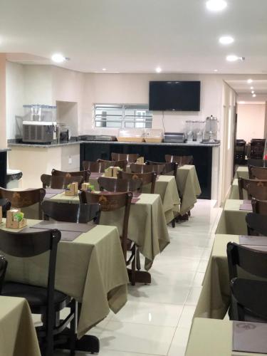 a restaurant with tables and chairs and a kitchen at Attriun Hotel in Guarulhos