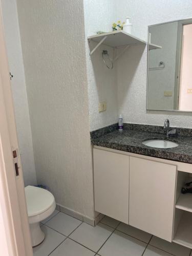a bathroom with a toilet and a sink and a mirror at 2 quartos a beira mar da Pajuçara in Maceió