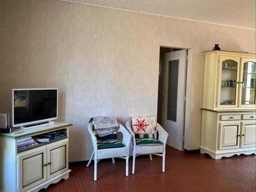 un salon avec deux chaises et une télévision dans l'établissement Villa 3 ch, jardin, wifi, proche plage et forêt, quartier calme - FR-1-336-99, à Longeville-sur-Mer