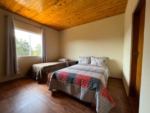1 dormitorio con 2 camas y ventana en Chácara das Palmeiras - 11 min do Capivari, en Campos do Jordão
