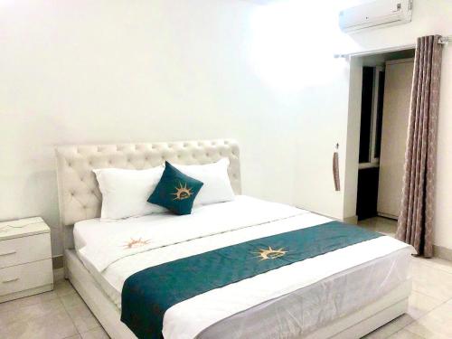 a bedroom with a white bed with blue and gold pillows at Holiday Hotel 2 in An Khê