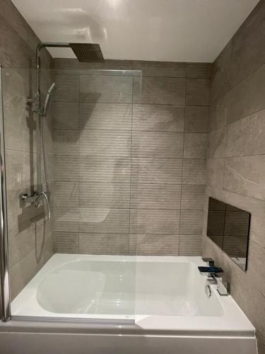 a bathroom with a tub and a glass shower at Stylish and Modern 2BR Apartment with Parking in Sheffield