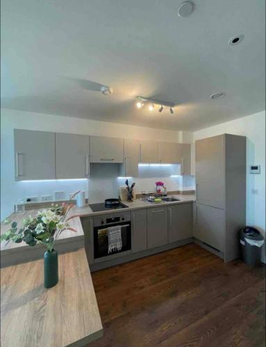 una cocina con armarios blancos y una mesa. en Modern New Airy 1 Bed Apartment LONDON cosy stays en Barking