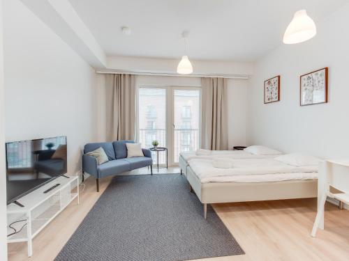 biały pokój z łóżkiem, kanapą i telewizorem w obiekcie SPOT Apartments - Turun satama w mieście Turku