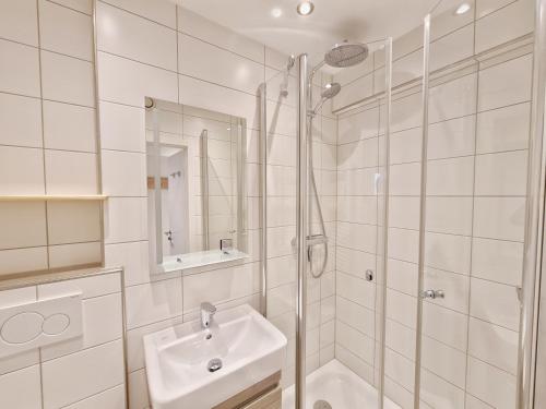 een witte badkamer met een wastafel en een douche bij Kaiserhof auf Norderney in Norderney