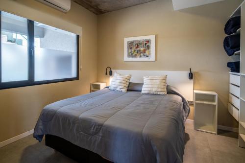 a bedroom with a large bed with a window at Apart Altos de Silenios in Pinamar