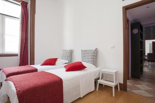 two beds in a white room with red pillows at FLH Baixa Comfortable Apartment in Lisbon