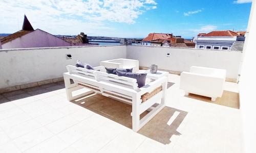 a balcony with white furniture on a roof at Figueira Penthouse by the Marina in Figueira da Foz