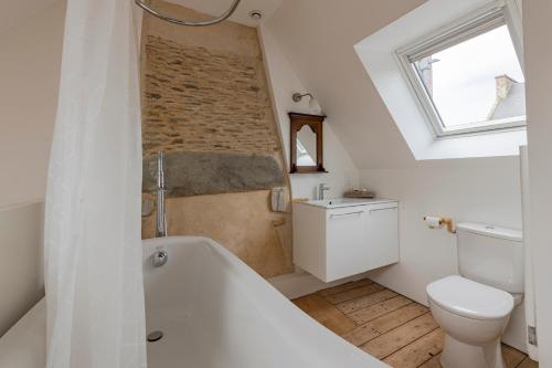 a bathroom with a white tub and a toilet and a window at Les Jeux du Vent -Saint Jacut de la mer in Saint-Jacut-de-la-Mer