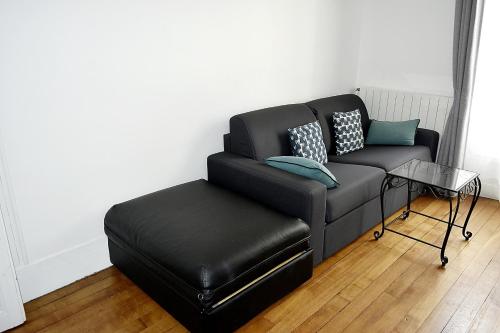 a black couch with pillows and a foot stool at CdH Lantiez in Paris