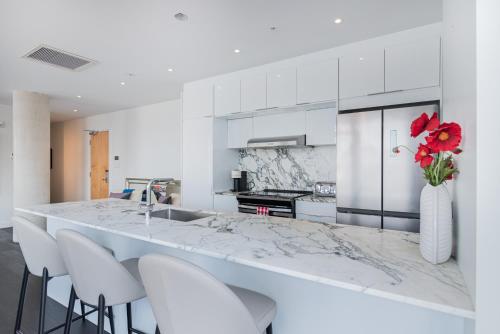 a kitchen with white cabinets and a counter with white chairs at Le Se7t Penthouses in Montreal