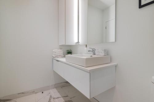 a white bathroom with a sink and a mirror at Le Se7t Penthouses in Montréal