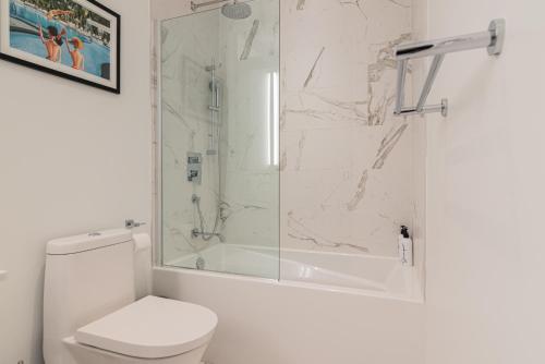 a white bathroom with a shower and a toilet at Le Se7t Penthouses in Montréal
