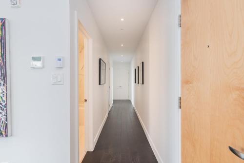 an empty hallway with white walls and wood floors at Le Se7t Penthouses in Montréal