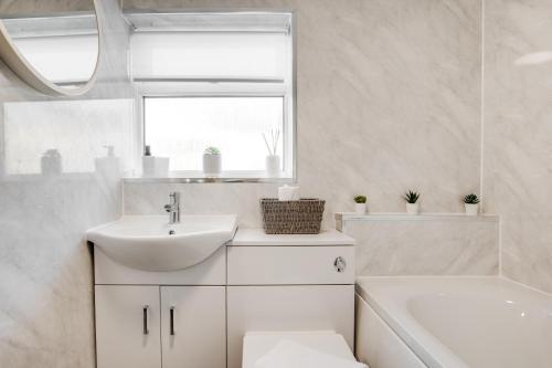 a white bathroom with a sink and a tub at Silver Stag Properties, 3 BR Gem with 2 Baths in Hugglescote