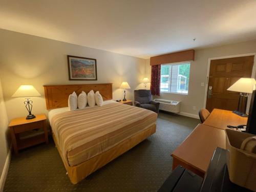 a hotel room with a large bed and a desk at Stagecoach Inn Woodville in Woodville