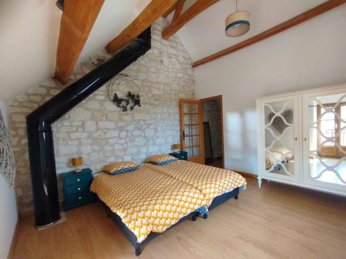 une chambre avec un lit et un mur en pierre dans l'établissement Jolie maison au calme, à Châteauvieux