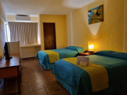 a hotel room with three beds and a television at Hotel Plaza Cozumel in Cozumel