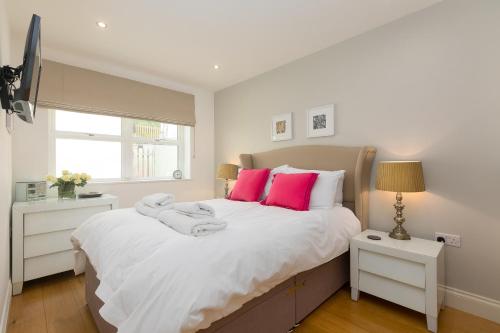 a bedroom with a large white bed with pink pillows at 2 Four Seasons in St Ives