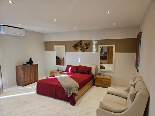 1 dormitorio con cama roja y sofá en Double bedroom in shared Penthouse Apartment - Seabreeze Terraces, en St Paul's Bay