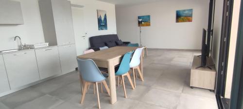 une cuisine avec une table en bois et des chaises bleues dans l'établissement T3 neuf, vue mer, à Pietrosella