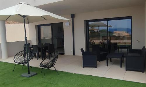 une terrasse avec des chaises, des tables et un parasol dans l'établissement T3 neuf, vue mer, à Pietrosella