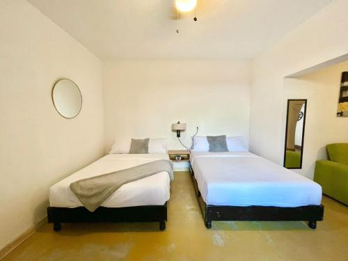 2 camas en una habitación con sofá verde en Confortable Loft MN 960 C Centro Mty cerca de todo, en Monterrey