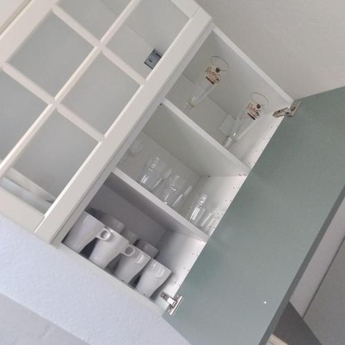 a white cupboard with some glasses in it at Monteurzimmer in Hamburg West bei Hansezimmer in Hamburg
