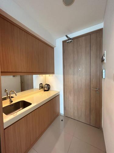 una cocina con armarios de madera y fregadero en QnM Rooms at Treepark City, en Tjikokol