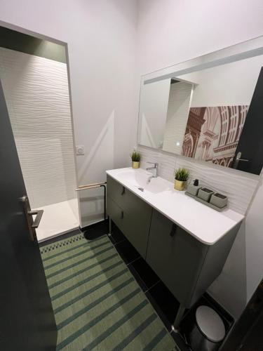 une salle de bain avec un lavabo et un miroir dans l'établissement La Suite Triangle d'or, à Bordeaux