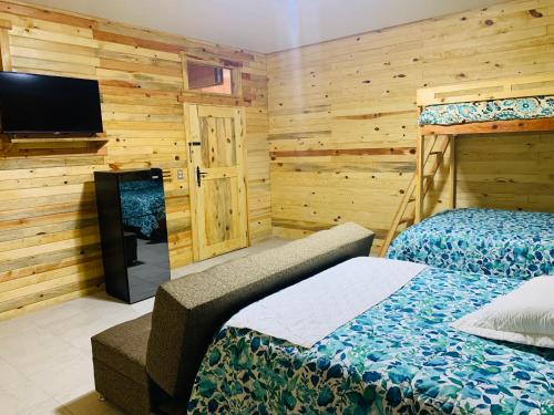 a bedroom with two beds and a flat screen tv at Rimusa Inn in Creel