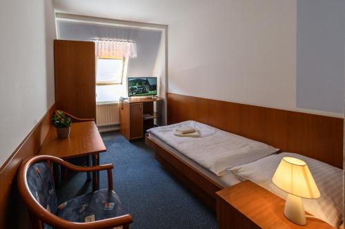 a bedroom with a bed and a desk and a television at Sport-V-Hotel in Hrotovice