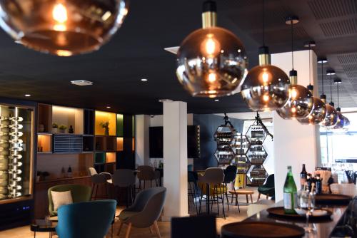 a restaurant with tables and chairs and chandeliers at Holiday Inn Dijon Sud - Longvic by IHG in Dijon