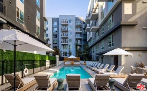 ロサンゼルスにあるDTLA Luxury Condo with Pool, Gym, Work Pods & Conference Roomの建物の隣にプール(椅子、パラソル付)