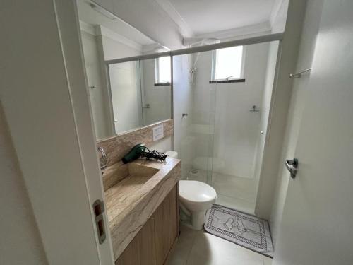 uma casa de banho com um lavatório, um WC e um espelho. em Apartamento Novo Praia de Bombas em Bombinhas